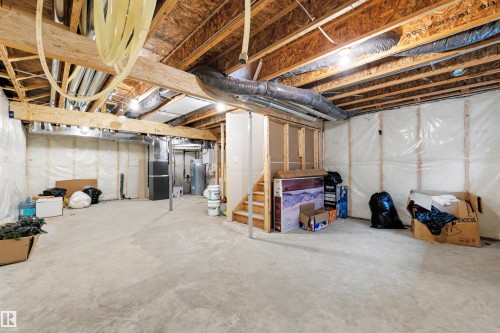 Unfinished basement featuring exposed wood joists and subflooring, concrete flooring, visible framing, and a wooden staircase - 3173 Checknita Way, Edmonton, AB 