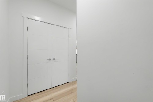 Double white doors with horizontal paneling, brushed chrome hardware, and light wood-finish flooring - 3173 Checknita Way, Edmonton, AB 