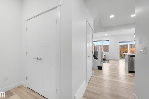 Modern interior hallway featuring light wood-finish flooring and contemporary white doors with chrome hardware - 3173 Checknita Way, Edmonton, AB 