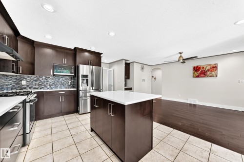 Modern kitchen featuring espresso cabinetry, stainless steel appliances, a white quartz island, and a mosaic tile backsplash - 16124 76 Street, Edmonton, AB 