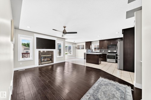 Spacious open-concept living area featuring dark wood-finish flooring, a contemporary ceiling fan, and recessed lighting - 16124 76 Street, Edmonton, AB 