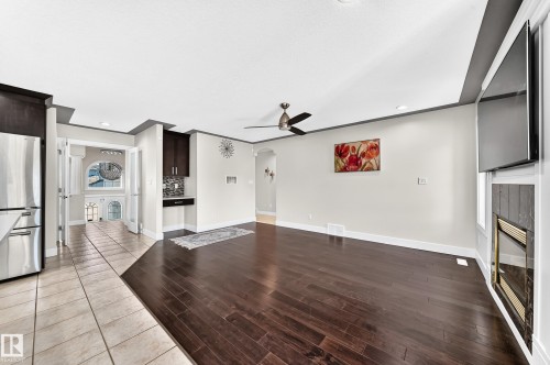 Open-concept living area featuring rich wood-finish flooring, a contemporary ceiling fan, and recessed lighting - 16124 76 Street, Edmonton, AB 