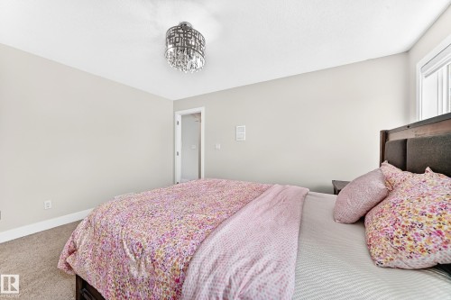 Bedroom featuring a contemporary chandelier, neutral wall paint, white trim, and a window providing natural light - 16124 76 Street, Edmonton, AB 