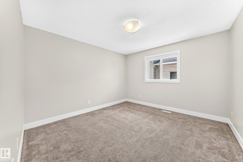 Carpeted interior room featuring light gray wall paint, white trim, a single window, and a flush-mount ceiling light fixture - 16124 76 Street, Edmonton, AB 