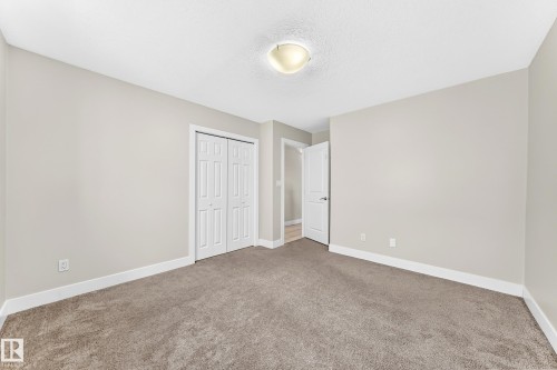 Spacious room with neutral-toned carpeting, light gray walls, and white trim - 16124 76 Street, Edmonton, AB 