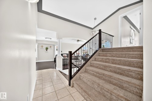 Carpeted staircase with dark wood-finish handrail and black metal spindles - 16124 76 Street, Edmonton, AB 