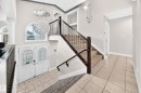 Foyer featuring a dual entry door with decorative glass inserts, an arched transom window, and a multi-tiered crystal chandelier - 16124 76 Street, Edmonton, AB 