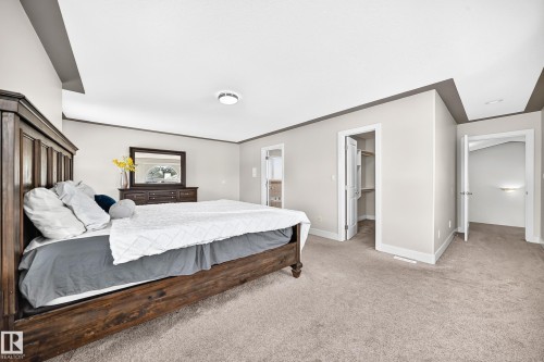 Spacious bedroom featuring light neutral wall tones, contrasting dark trim, and soft carpeting - 16124 76 Street, Edmonton, AB 