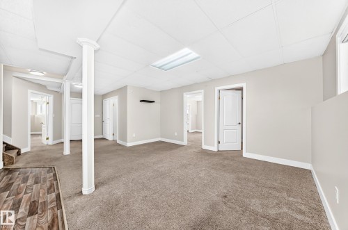 Spacious lower-level area featuring neutral carpeting, a drop ceiling with recessed lighting, and light gray painted walls - 16124 76 Street, Edmonton, AB 