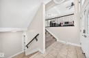 Foyer entry featuring ceramic tile flooring, a white paneled front door with decorative glass inserts, and a black wrought iron staircase railing - 16124 76 Street, Edmonton, AB 