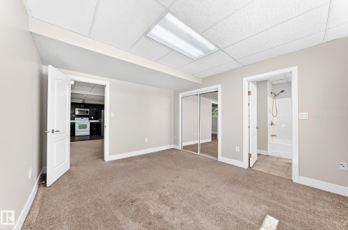 Carpeted interior room featuring neutral wall tones, white trim, and a drop ceiling with recessed lighting - 16124 76 Street, Edmonton, AB 