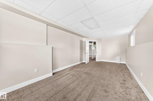 Spacious room featuring new carpeting, neutral wall paint, white trim, a drop ceiling with integrated lighting, and an egress window - 16124 76 Street, Edmonton, AB 