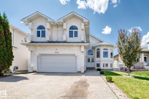 Stucco-clad exterior with prominent arched windows, a two-car garage, and a curved bay window feature - 16124 76 Street, Edmonton, AB 