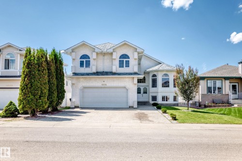 Two-story residence featuring a two-car garage, arched windows, and a light-colored stucco exterior - 16124 76 Street, Edmonton, AB 