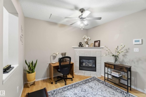 Interior space featuring wood-finish flooring, a corner fireplace with a tiled surround and mantel, a ceiling fan with integrated lighting, and neutral wall tones - 3117 32 Avenue, Edmonton, AB 