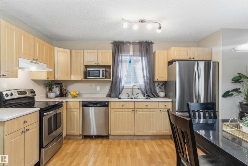 Kitchen featuring light wood-finish cabinetry, stainless steel appliances, laminate countertops, and wood-finish flooring - 3117 32 Avenue, Edmonton, AB 
