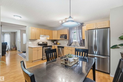 Modern kitchen featuring light wood cabinetry, stainless steel appliances, light countertops, and wood-finish flooring - 3117 32 Avenue, Edmonton, AB 