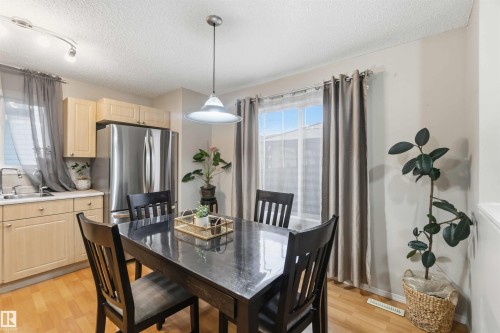 Dining area featuring a contemporary pendant light, wood-finish flooring, and natural light from a window with drapes - 3117 32 Avenue, Edmonton, AB 
