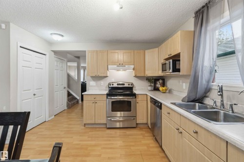 Kitchen featuring light wood-finish cabinetry, stainless steel appliances, a double basin sink, and wood-look flooring - 3117 32 Avenue, Edmonton, AB 