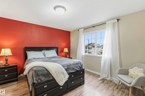 Bedroom featuring a large multi-pane window, wood-finish flooring, and a flush-mount ceiling light fixture - 3117 32 Avenue, Edmonton, AB 