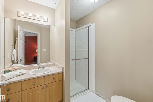 Bathroom featuring a light-toned vanity with an integrated sink, a large wall mirror, and a four-bulb light fixture - 3117 32 Avenue, Edmonton, AB 