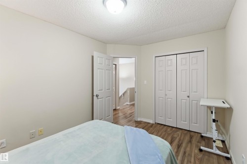 Bedroom featuring light-toned walls, wood-finish flooring, white bi-fold closet doors, and white trim - 3117 32 Avenue, Edmonton, AB 