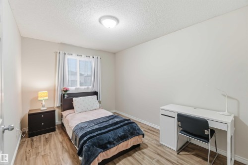 Bedroom featuring wood-finish flooring, a window with curtains, and a ceiling-mounted light fixture - 3117 32 Avenue, Edmonton, AB 