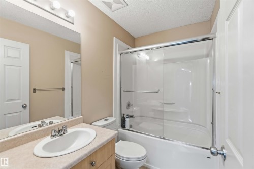 Bathroom featuring a vanity with an integrated sink, a full-width mirror, and a combination bathtub and shower with sliding glass doors - 3117 32 Avenue, Edmonton, AB 