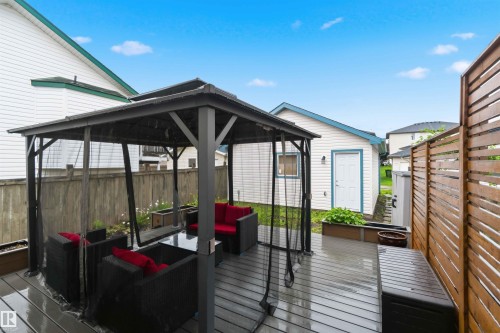Expansive outdoor deck featuring a dark grey gazebo with netting, grey composite decking, a horizontal slat privacy fence, and built-in planters - 3117 32 Avenue, Edmonton, AB 
