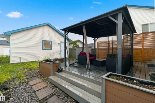 Composite decking with integrated steps leading to a gazebo, featuring privacy screening and a slatted wood fence backdrop - 3117 32 Avenue, Edmonton, AB 