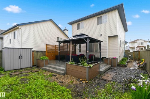 Rear exterior featuring a covered patio, raised garden beds, a storage shed, and a privacy fence - 3117 32 Avenue, Edmonton, AB 