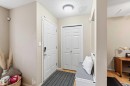 Front entry featuring a solid white door with smart lock hardware, a bifold closet door, and wood-finish flooring - 3117 32 Avenue, Edmonton, AB 