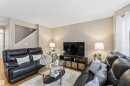 Living area featuring light wood-finish flooring, neutral wall paint, and a staircase with white risers and handrail - 3117 32 Avenue, Edmonton, AB 