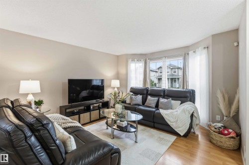 Living area featuring light wood-finish flooring, neutral wall tones, and a bay window with multiple panes - 3117 32 Avenue, Edmonton, AB 