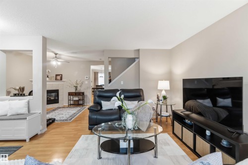 Living area featuring wood-finish flooring, light neutral wall tones, a built-in window bench, and a gas fireplace with a light-colored mantel - 3117 32 Avenue, Edmonton, AB 