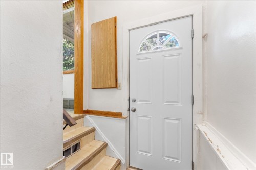 White paneled entry door with an arched decorative glass insert and polished nickel hardware - 9315 86 Street, Edmonton, AB 