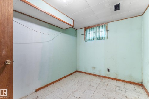 Room featuring light blue walls, wood-finish trim, and white tiled flooring - 9315 86 Street, Edmonton, AB 