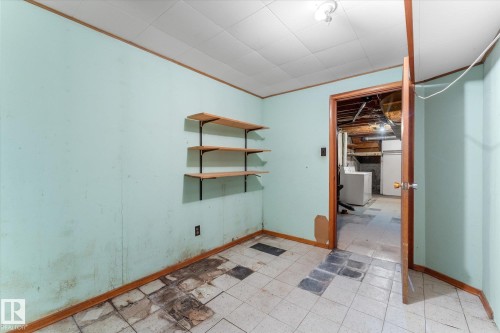 Room featuring light blue walls, wood-finish trim, and a drop ceiling - 9315 86 Street, Edmonton, AB 