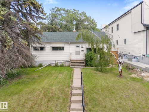 White siding residence with a green shingle roof, front porch with wooden steps, and a concrete pathway - 9315 86 Street, Edmonton, AB 