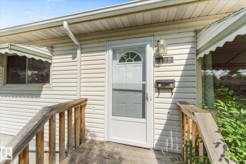 Front entry featuring a storm door with arch and sidelight details, house numbers, and an exterior wall light - 9315 86 Street, Edmonton, AB 