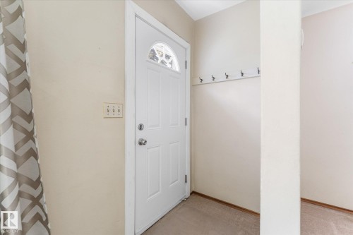 Entryway featuring a white paneled door with an arched glass insert, light beige wall paint, and carpet flooring - 9315 86 Street, Edmonton, AB 