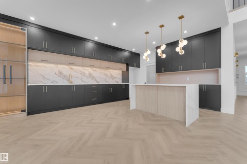 Modern kitchen featuring dark cabinetry, lighter wood-finish accents, and a waterfall island - 7677 Kimiwan Crescent, Edmonton, AB 