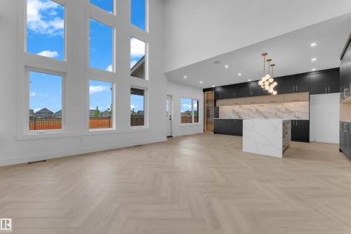 Contemporary open-concept interior featuring a soaring two-story ceiling and extensive window wall - 7677 Kimiwan Crescent, Edmonton, AB 