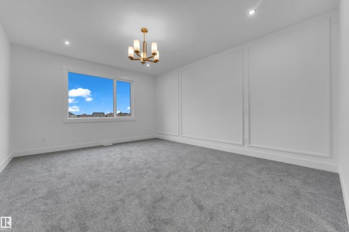 Bright interior room featuring a large window, recessed lighting, and a modern chandelier - 7677 Kimiwan Crescent, Edmonton, AB 