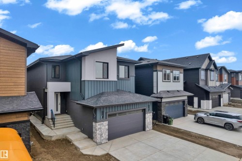 Modern multi-level residence featuring a contrasting exterior of vertical blue siding and white stucco accents - 7677 Kimiwan Crescent, Edmonton, AB 