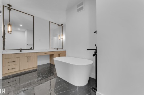 Spacious bathroom featuring a freestanding soaking tub, dual vanity with wood-finish cabinetry, black marble-look tile flooring, and contrasting matte black fixtures - 7677 Kimiwan Crescent, Edmonton, AB 