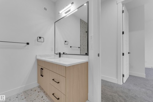 Modern bathroom vanity with wood-finish cabinetry, white countertop, and integrated sink - 7677 Kimiwan Crescent, Edmonton, AB 