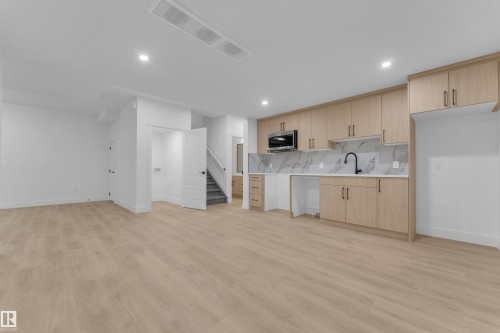 Open-concept living space featuring wood-finish flooring and recessed lighting - 7677 Kimiwan Crescent, Edmonton, AB 