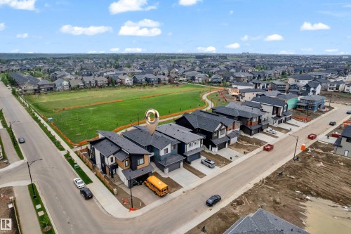 Modern residential property featuring a dark gray roof, two-car garage, and a concrete driveway - 7677 Kimiwan Crescent, Edmonton, AB 