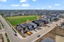 Modern residential property featuring a dark gray roof, two-car garage, and a concrete driveway - 7677 Kimiwan Crescent, Edmonton, AB 